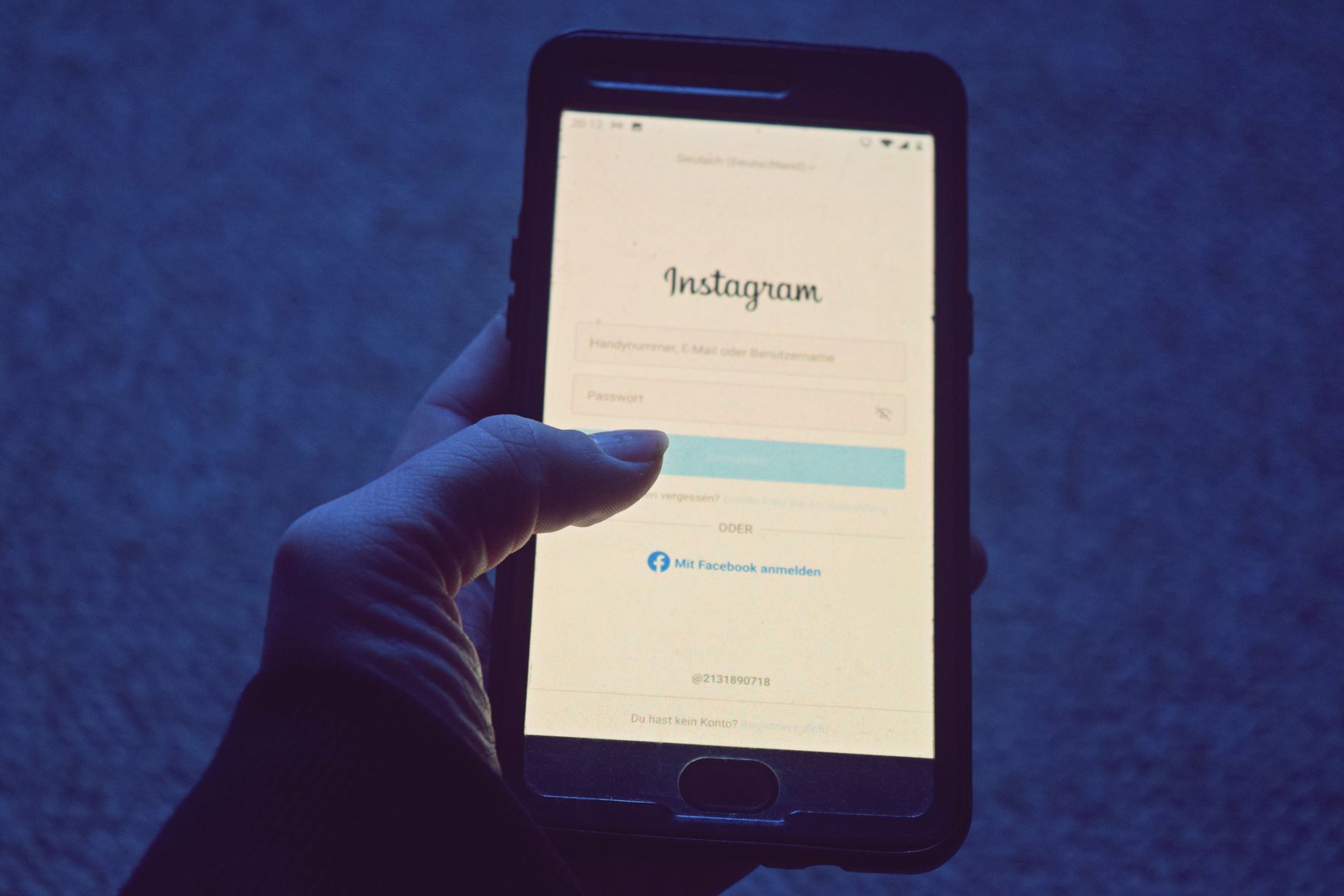 Une main tient un smartphone affichant une page de connexion sur son écran éclairé.
